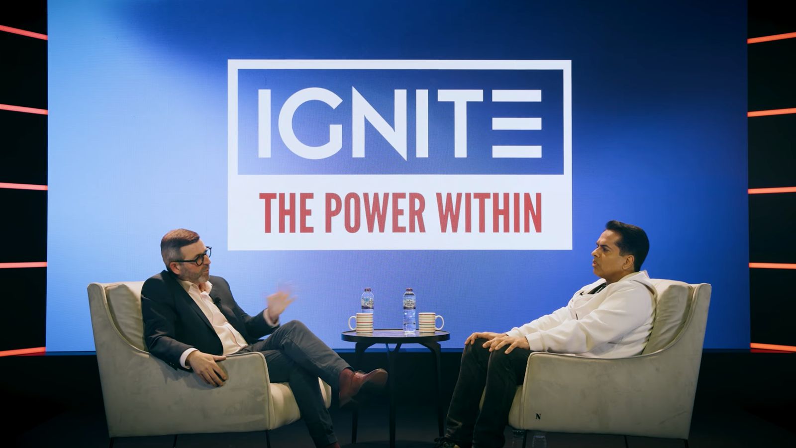 An episode of the IGNITE podcast being recorded: two guests in armchairs in front of the LED wall
