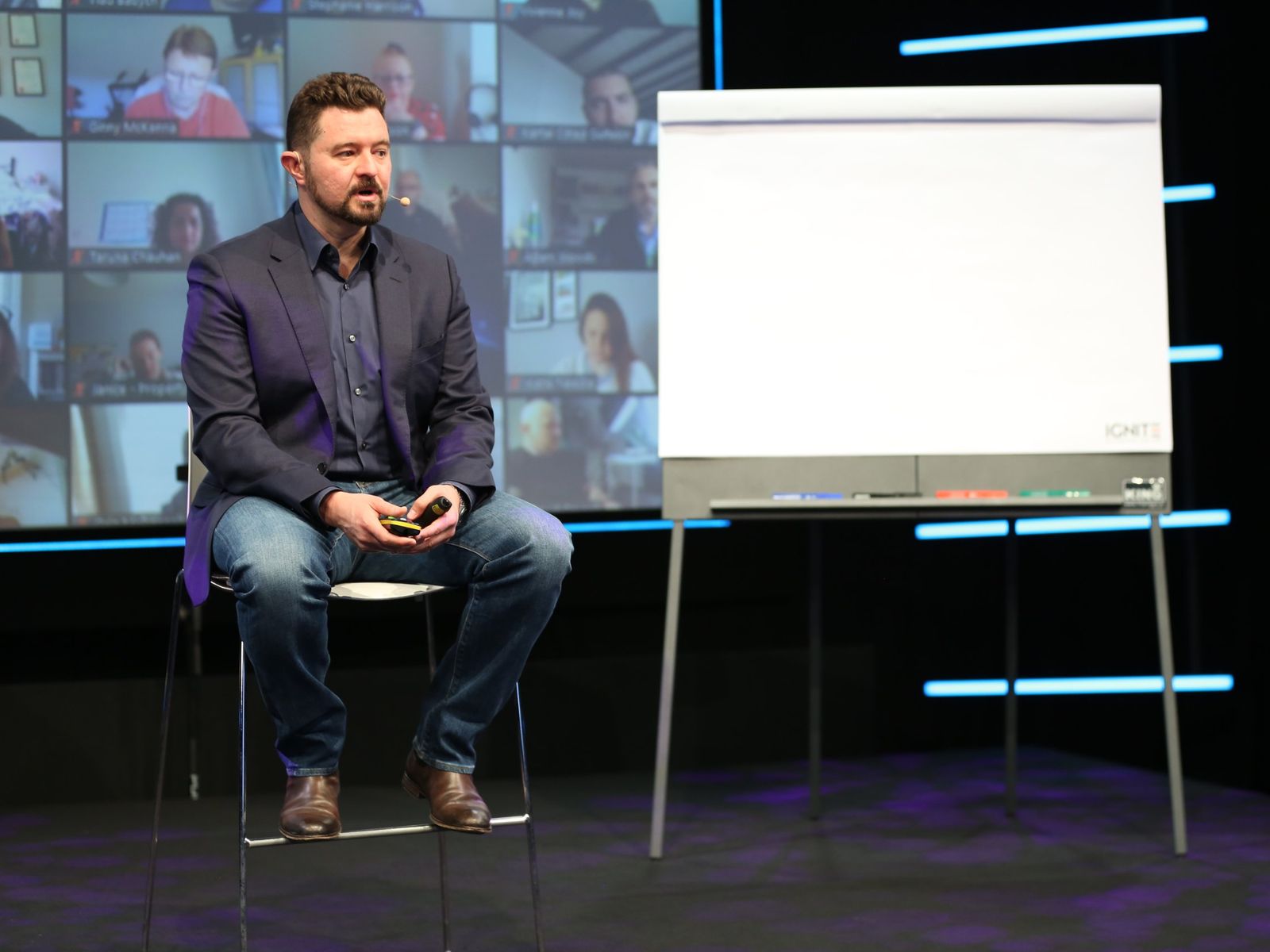 Daniel Priestley speaking on stage at IGNITE Studios, with the remote audience on the screens behind him