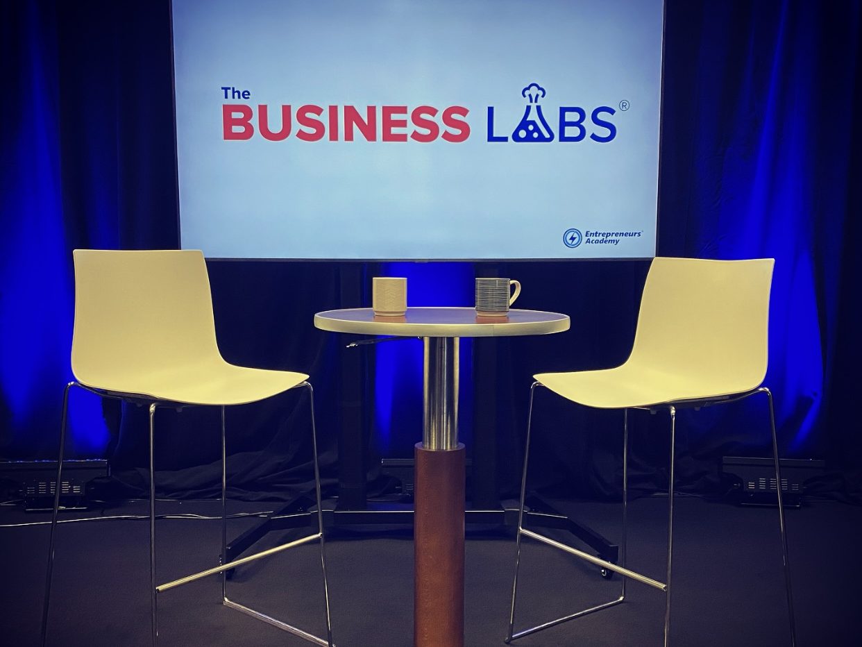 The Studio B interview set: two chairs and a table in front of a branded screen